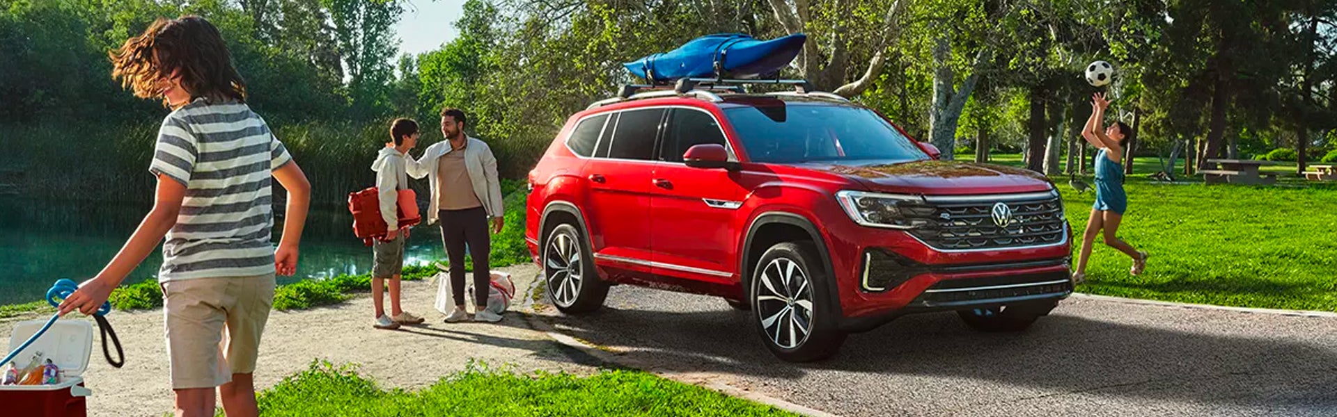 people playing around Volkswagen Atlas parked near lake